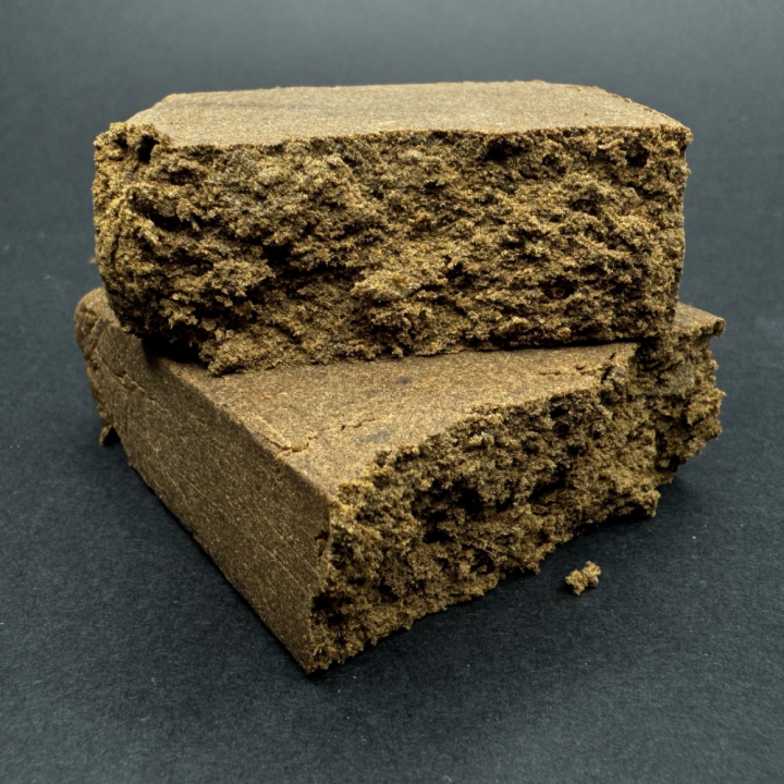 Vista pieza de 100 gramos de Ketama CBG partida en 2 donde se aprecia la textura de de la resina de cáñamo de perfil tradicional, con textura maleable, aroma terroso y matices especiados